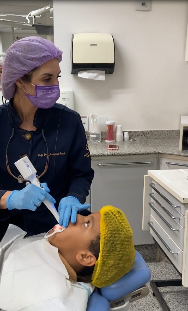 Dentista utilizando uma câmera intraoral durante o atendimento na cadeira